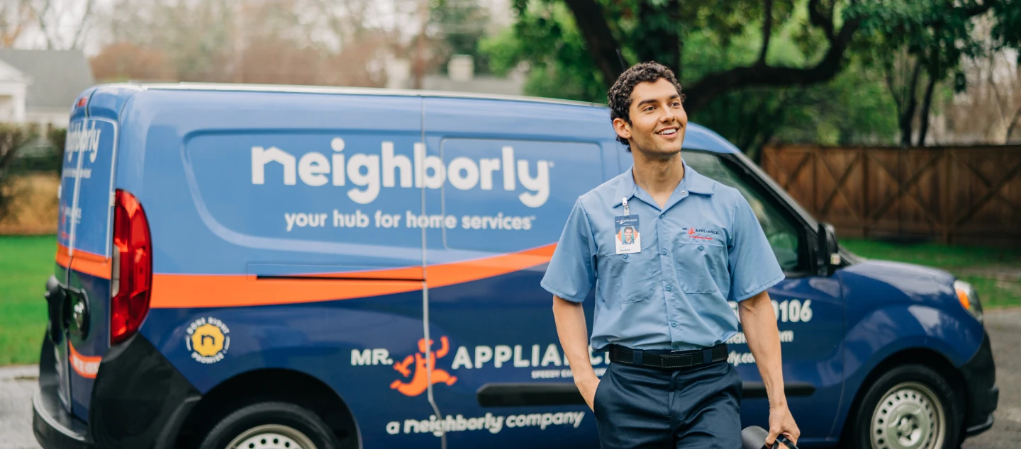 Service professional standing in front of Mr. Appliance van.