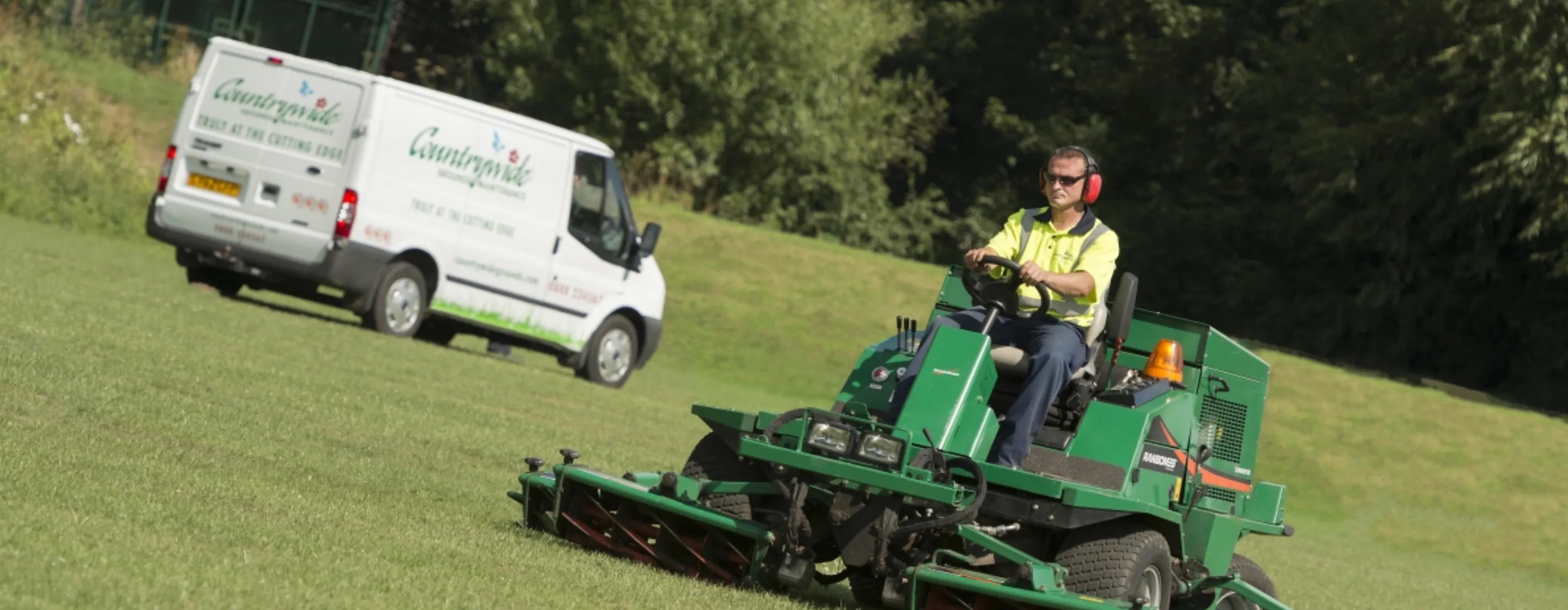 Countrywide Grounds Maintenance van and technician riding a lawn mower.
