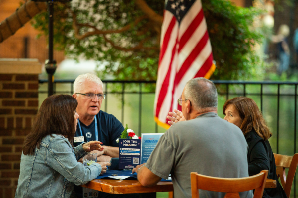 Group of people sitting outside at table.